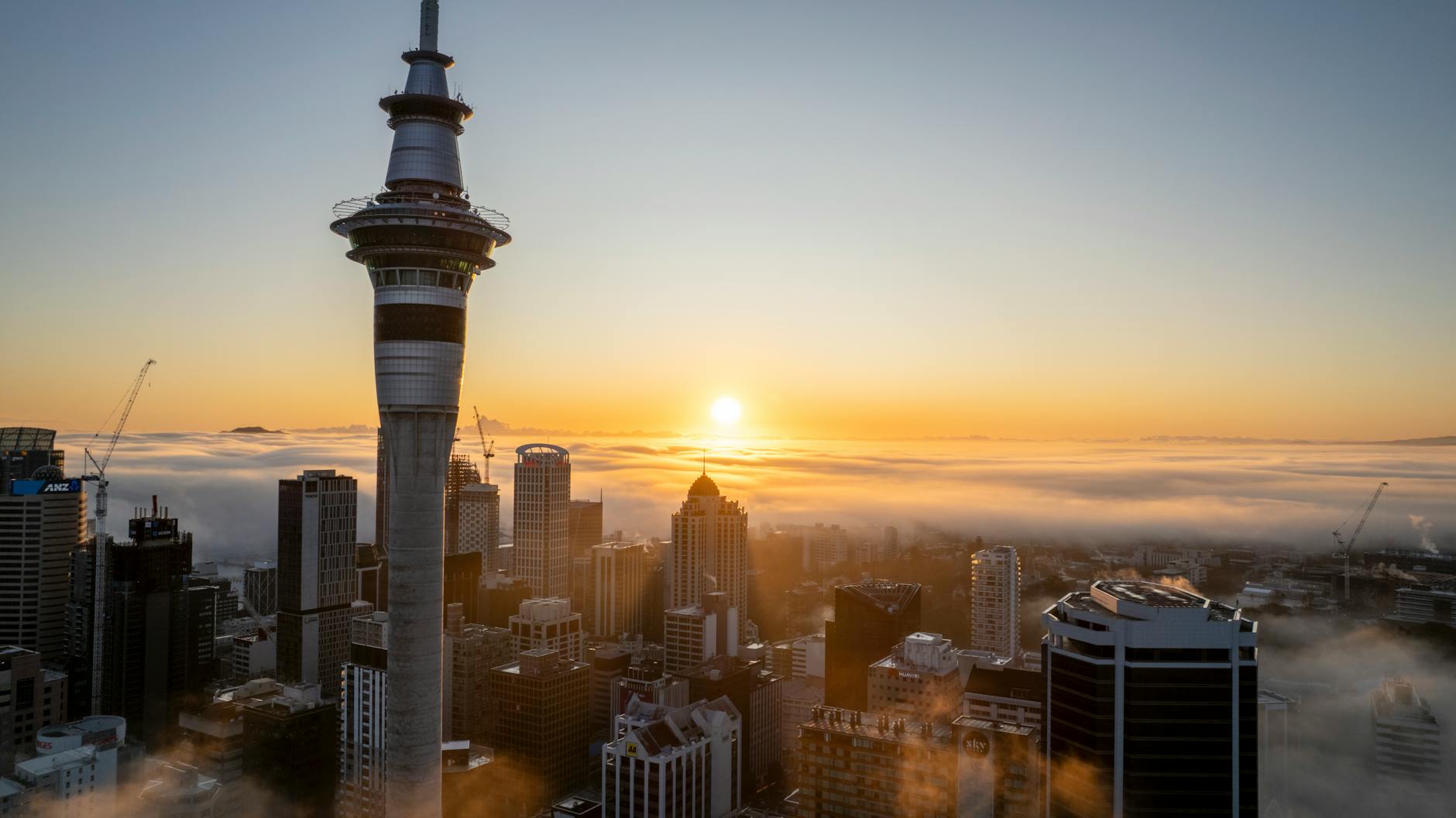 sky tower over buildings in auckland at sunset as one of the best travel destinations