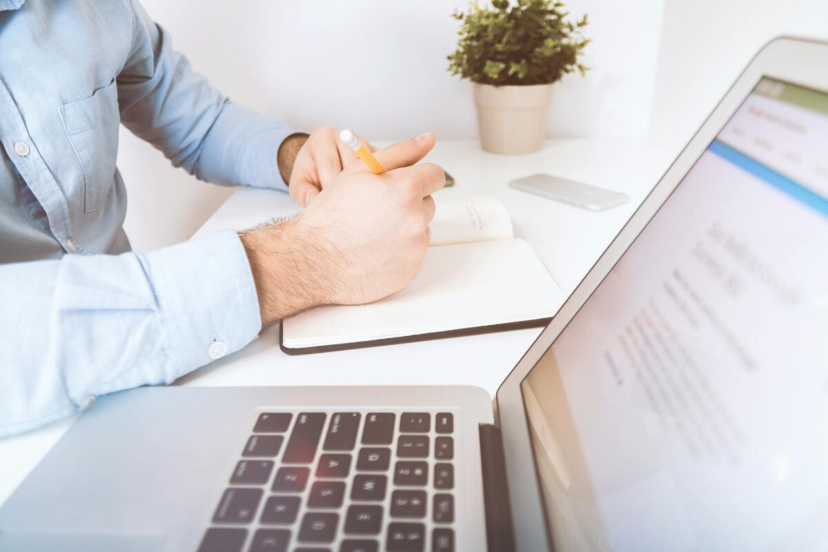 person holding pen and notebook to write effectively