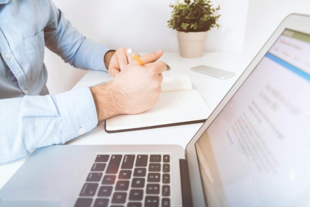 person holding pen and notebook to write effectively