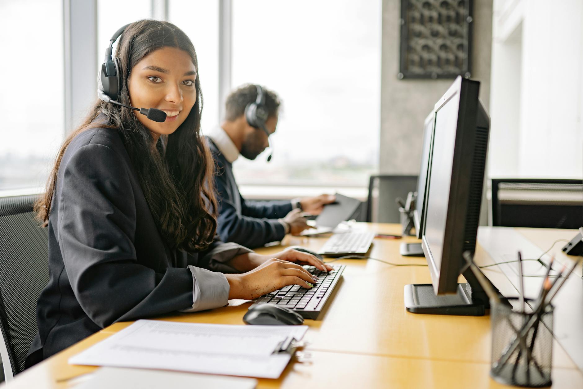 a smiling woman working in a call center while looking at camera